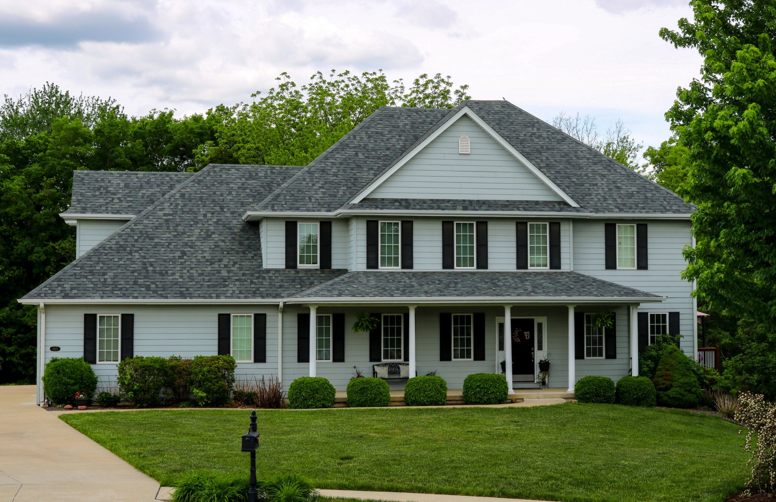 grey shingle rood on white house with black shutters