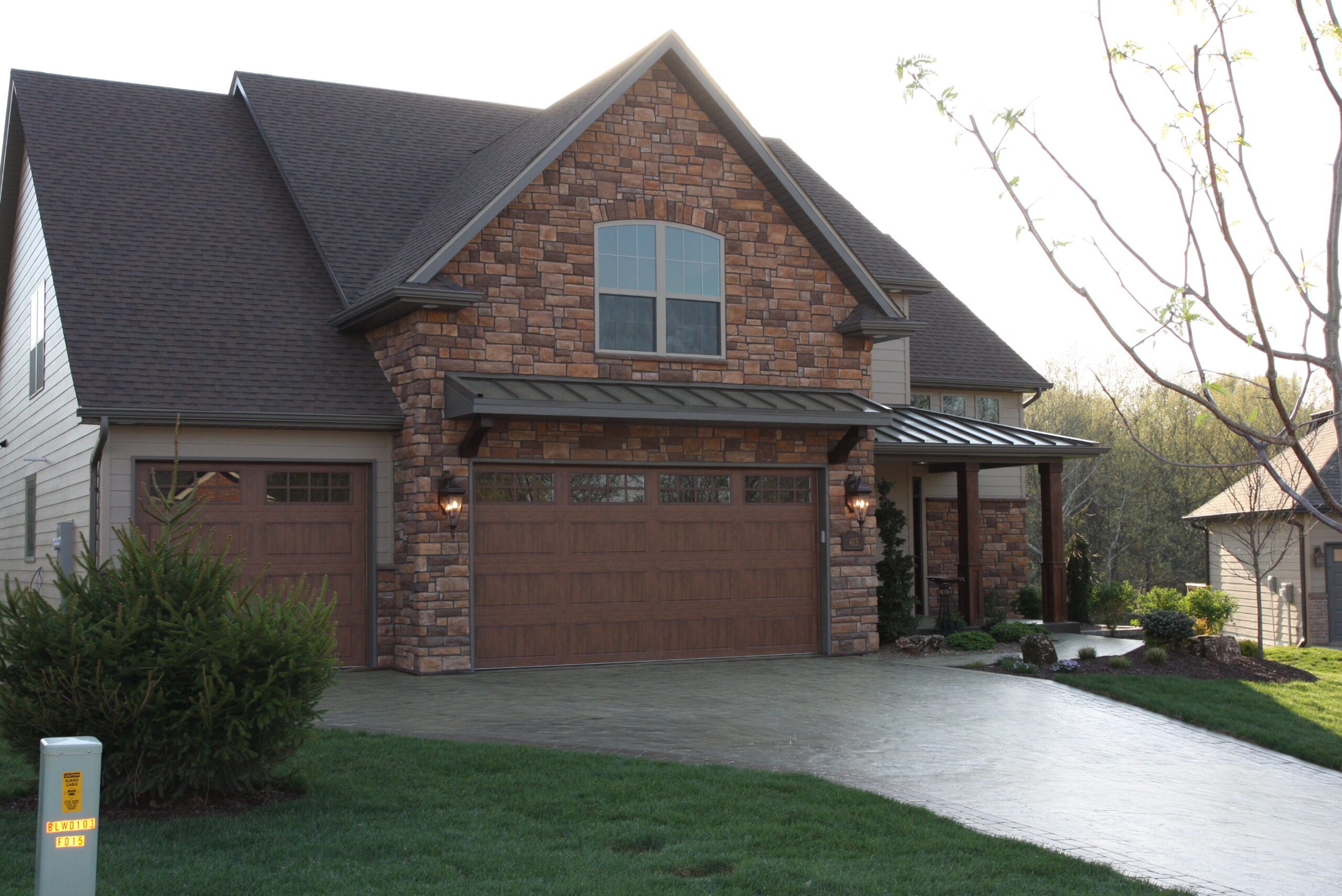 Brown and brick house with black metal roof porches