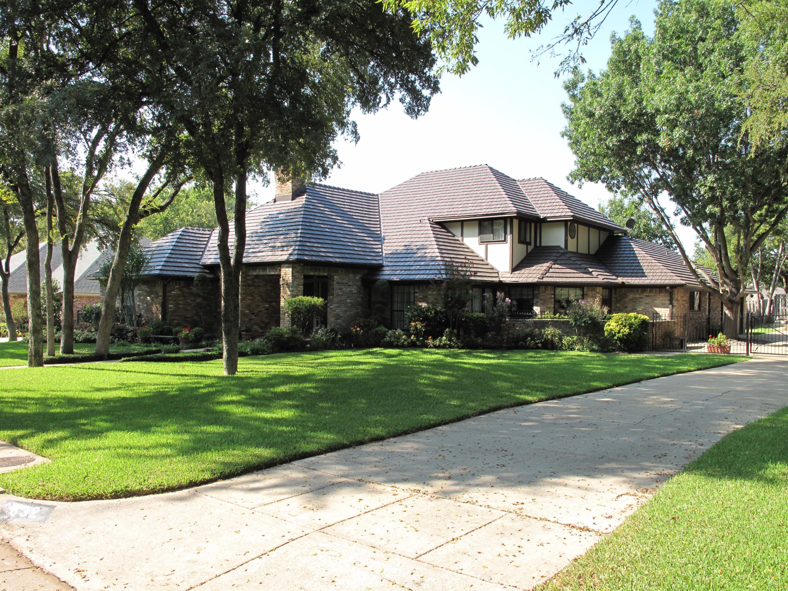 Large home with multi-layered roof and brown shingles.