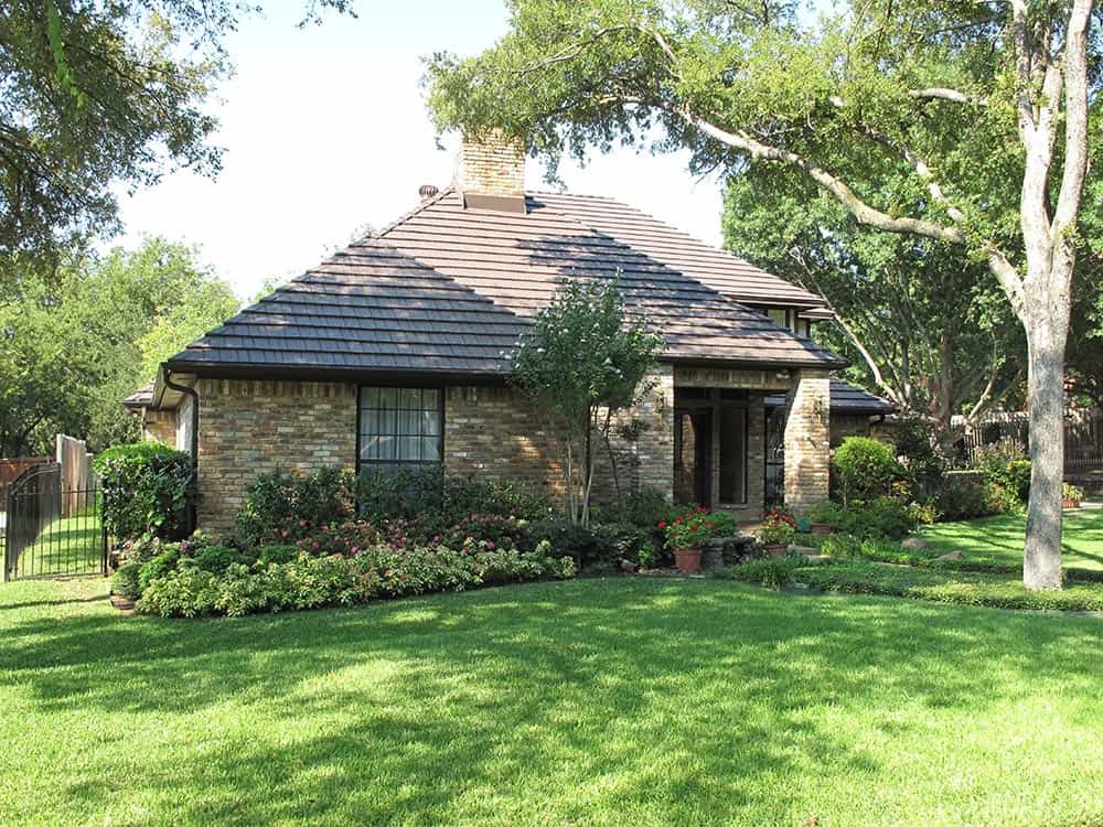 Stone home with brown shingle roofing