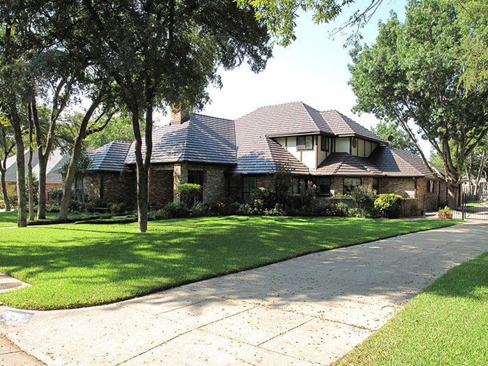 Large home with multi-layered roof and brown shingles.