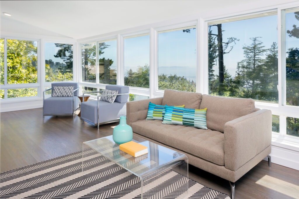 Bright solarium-style sunroom with light colored furniture and a striped area rug