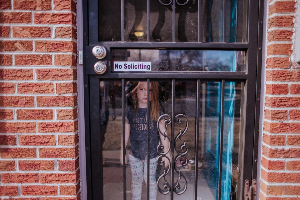 Toddler standing inside house with storm door adding a layer of security
