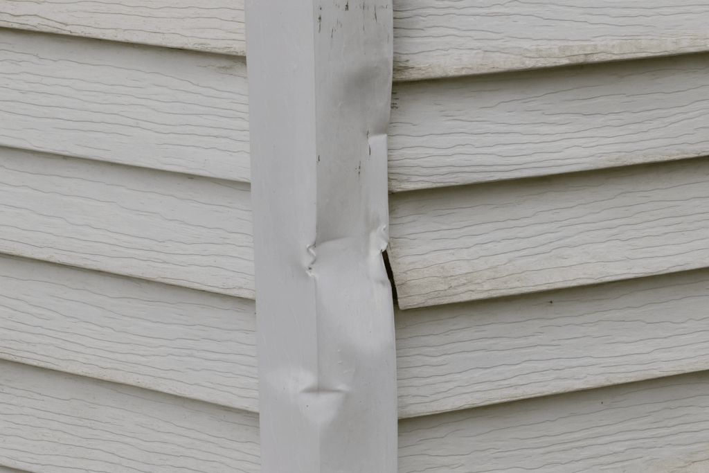Damaged aluminum siding on a home exterior showing a need for maintenance and repairs